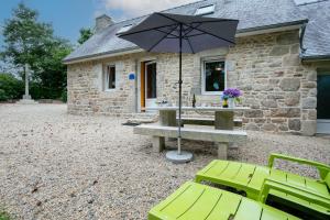 a picnic table with an umbrella in front of a building at Gîte Ty Nevez in Lanvellec