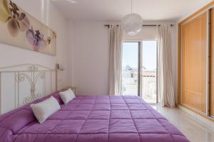 a purple bed in a white room with a window at Apartamento Corazón de Nerja in Nerja