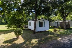 a white cabin in a yard with a tree at Mobilhome du Soleil in Saint-Pompont