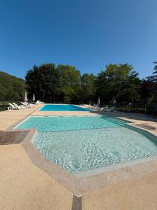 a swimming pool with blue water and chairs and trees at Mobilhome du Soleil in Saint-Pompont +9 photos