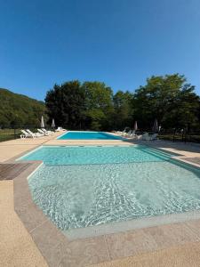 a blue swimming pool with chairs and trees at Mobilhome du Soleil in Saint-Pompont