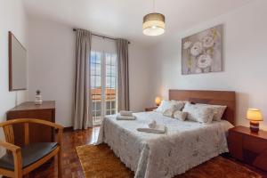 a bedroom with a bed and a chair and a window at Apartamento Maria in Canhas