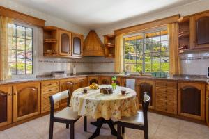 a kitchen with a table and chairs and windows at Apartamento Maria in Canhas