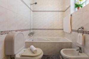 a bathroom with a toilet and a tub and a sink at Apartamento Maria in Canhas +32 photos