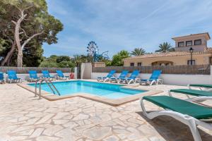a swimming pool with lounge chairs and a villa at Apartamentos Karin 2ºe in Cala d´Or