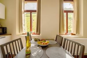 a dining room table with a bottle of wine and a bowl of fruit at Alte Stadtvilla am Weinberg 4 in Traben-Trarbach