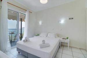 a white bedroom with a bed and a balcony at S9 room in Nikiana +11 photos