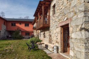 a stone building with a balcony and a table and chairs at El Mirador de Babia in Ríolago
