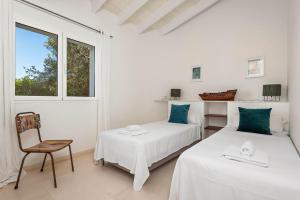 two beds in a room with a chair and a window at Villa Mariposa in Sant Lluis +34 photos
