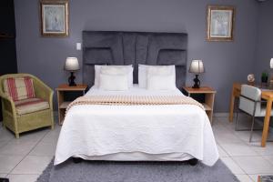 a bedroom with a large bed and two chairs at Bachelor suite in Rustenburg in Rustenburg
