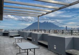 a patio with tables and benches and a view of a mountain at Modern loft with panoramic views in Monterrey
