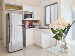 a white kitchen with a refrigerator and a vase of flowers at Diamond in Bangkok +13 photos