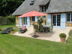 a patio with a table and chairs and an umbrella at Le Pressoir in Cresseveuille