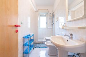 a white bathroom with a sink and a toilet at L'acquario in Villasimius +23 photos