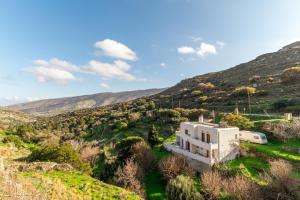 a white house in the middle of a mountain at Moraki Apartment 2 Andros in Korthi