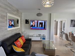 a living room with a black couch and a tv at Corralejo Branded Residensed in Corralejo