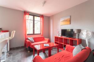 a living room with red furniture and a tv at T3 ensoleillé le Vignemale in Lourdes