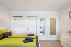 a bedroom with a green bed and white walls at Schwarzwaldblick D App 8 mit Pool in Schönwald +11 photos