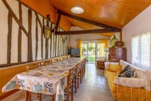 a dining room with a long table and a couch at Gite à la campagne in Ginestet