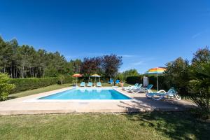 a pool with chairs and umbrellas in a yard at Gite à la campagne in Ginestet