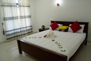 1 dormitorio con 1 cama grande con almohadas rojas y amarillas en Shady mango villa en Sigiriya
