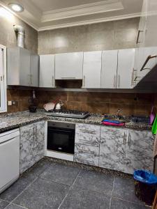 a kitchen with marble counter tops and white cabinets at Dar dyafa in Meknès