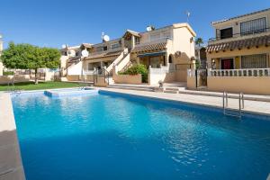 a blue swimming pool in front of a house at Heads 2 Holiday Homes Apartment in Villamartin