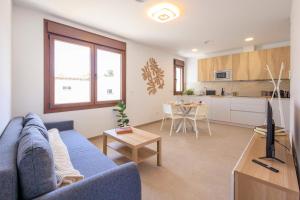 a living room with a blue couch and a kitchen at Apartamentos Turísticos Olivares in Mota del Cuervo