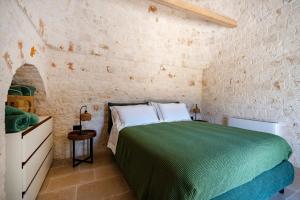 a bedroom with a green bed in a brick wall at Dimora Dormio in Monopoli