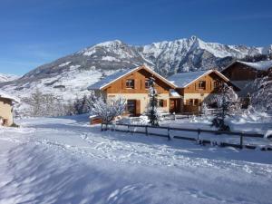 a house in the snow with mountains in the background at Chalet Garrigue aux Orres in Les Orres