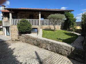 a house with a stone wall and a yard at Santa Baia in Veiga
