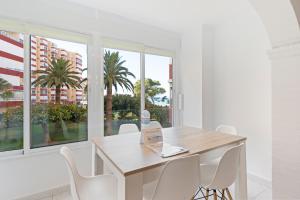 a white dining room with a wooden table and white chairs at Apartamento Sol Playa Torrox A55 in Torrox Costa