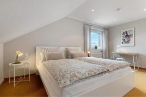 a white bedroom with a large bed and a window at Ferienwohnung Sämann in Oberkirch
