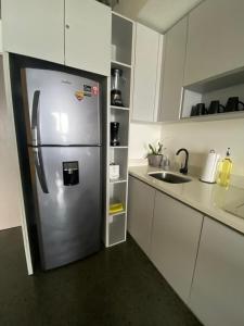 a stainless steel refrigerator in a kitchen with white cabinets at Modern loft with panoramic views in Monterrey