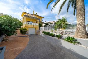 a yellow house with a palm tree in front of it at Villa Amador in L'Ampolla