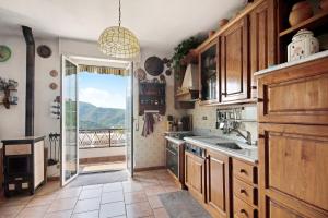 a kitchen with wooden cabinets and a large window at Ca Olivella in Casarza Ligure