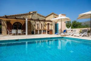 ein Pool mit Stühlen und Sonnenschirmen vor einem Haus in der Unterkunft Finca Soliva in Capdepera