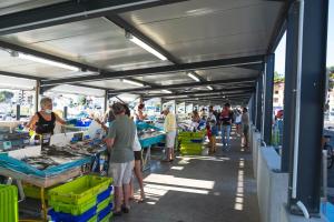 a group of people standing around a fish market at Villa Rénovée, 5min Plage in Seignosse +18 photos