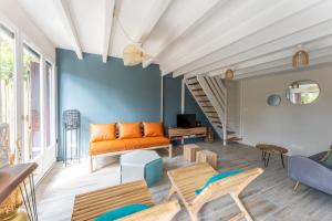 an orange couch in a living room with a blue wall at Villa Rénovée, 5min Plage in Seignosse