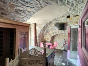 a room with a stone wall and pink chairs at Gite Sublime Spa, Piscine Indoor in Mostuéjouls