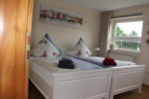a bedroom with a white bed with pillows and a window at Haus Deichbrise in Niebüll