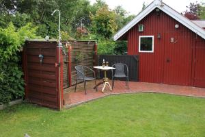 a patio with a table and a red shed at Haus Deichbrise in Niebüll