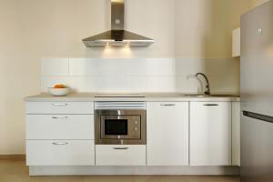 a kitchen with white cabinets and a microwave at Albamar 1a in Puerto de Mogán
