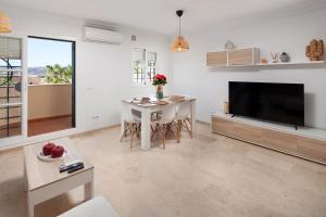 a living room with a television and a table with chairs at Baviera Homes Sunset and Golf in Caleta De Velez