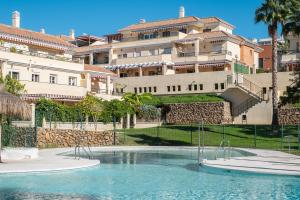 a swimming pool in front of a large building at Baviera Homes Sunset and Golf in Caleta De Velez