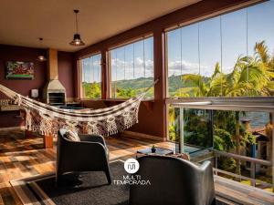 a living room with a hammock in a room with windows at Casa na Lagoa - Imaruí/SC in Imaruí
