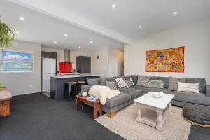 a living room with a couch and a table at Wharf Landing - Harbour View with Sunny Balcony, Walk to Town in Coromandel Town