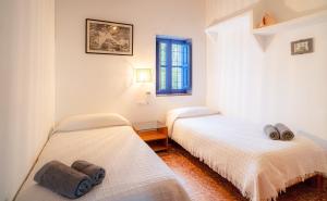 two beds in a room with white walls and a window at Casa can Pep Martí in Sant Francesc Xavier