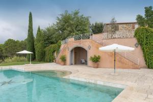 a swimming pool in front of a house with an umbrella at Villa Cava Alta in Riparbella