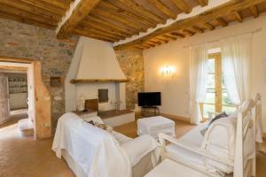 a living room with white chairs and a fireplace at Villa Cava Alta in Riparbella